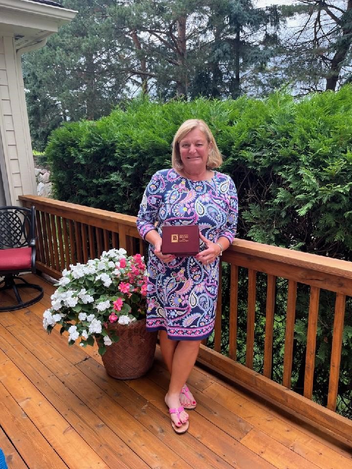 Picture of Terri Anthony-Ryan on an outdoor deck with flowers and her Hall of Fame plaque